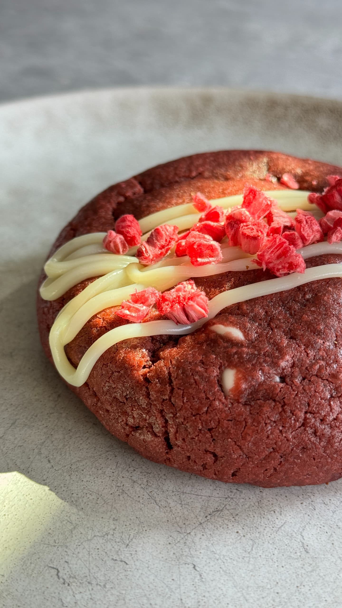 Red velvet cookie with raspberry cheesecake filling, sliced to show the creamy center.