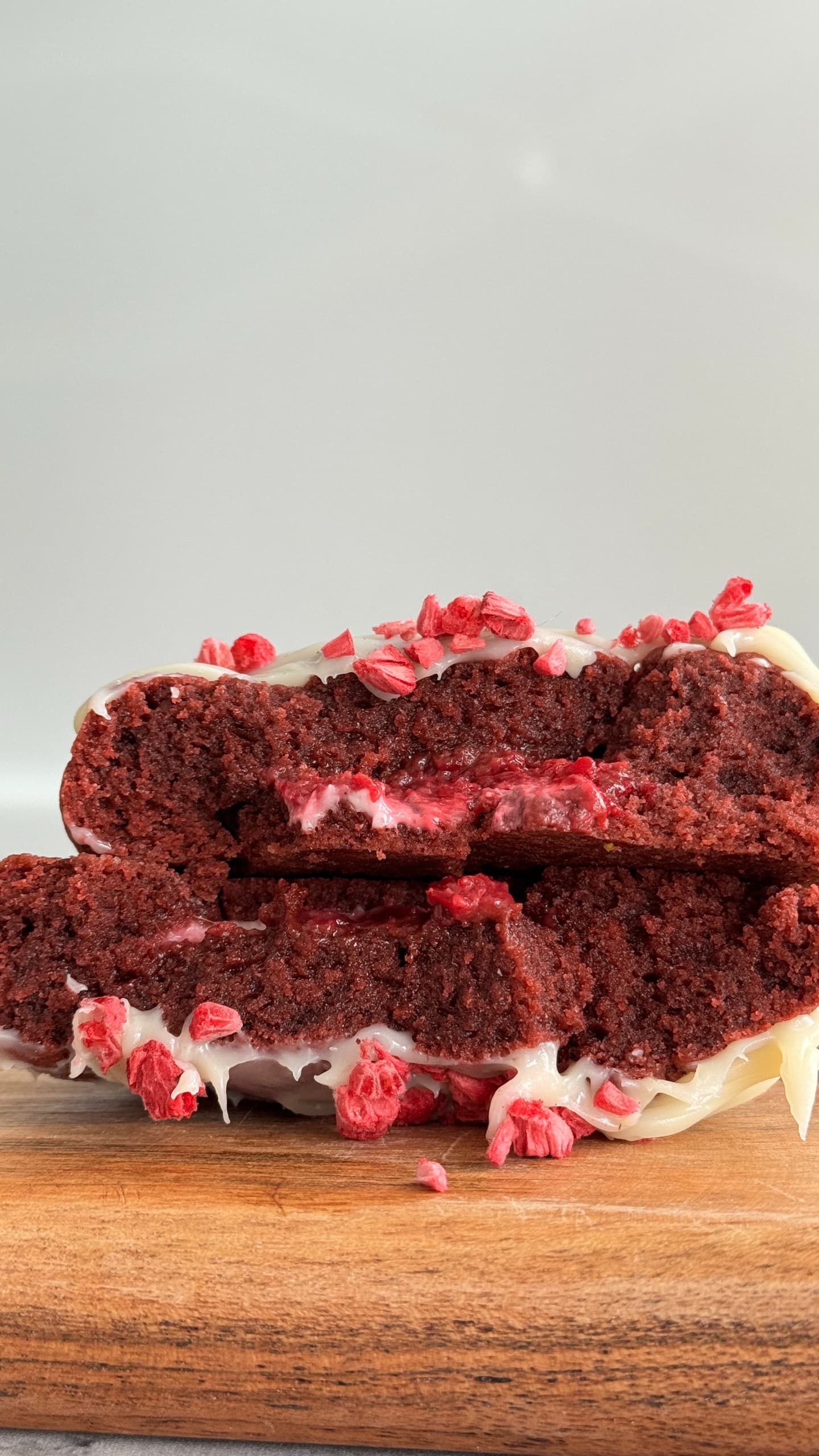 Red velvet cookie with raspberry cheesecake filling, sliced to show the creamy center.