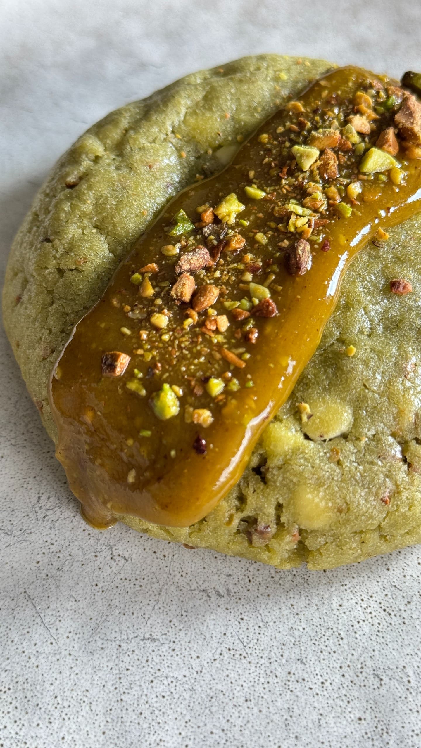 Soft pistachio cookies filled with creamy white chocolate and a smooth pistachio ganache center, showing a buttery, nutty texture with a melt-in-your-mouth appearance.
