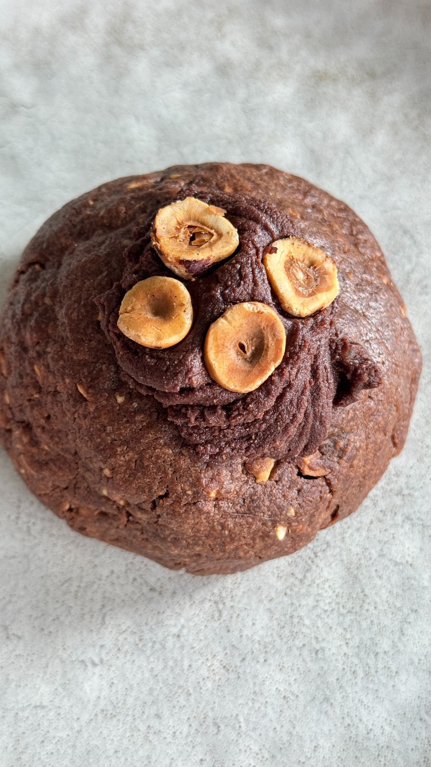 Nutella cookie topped with roasted hazelnuts on a light background.