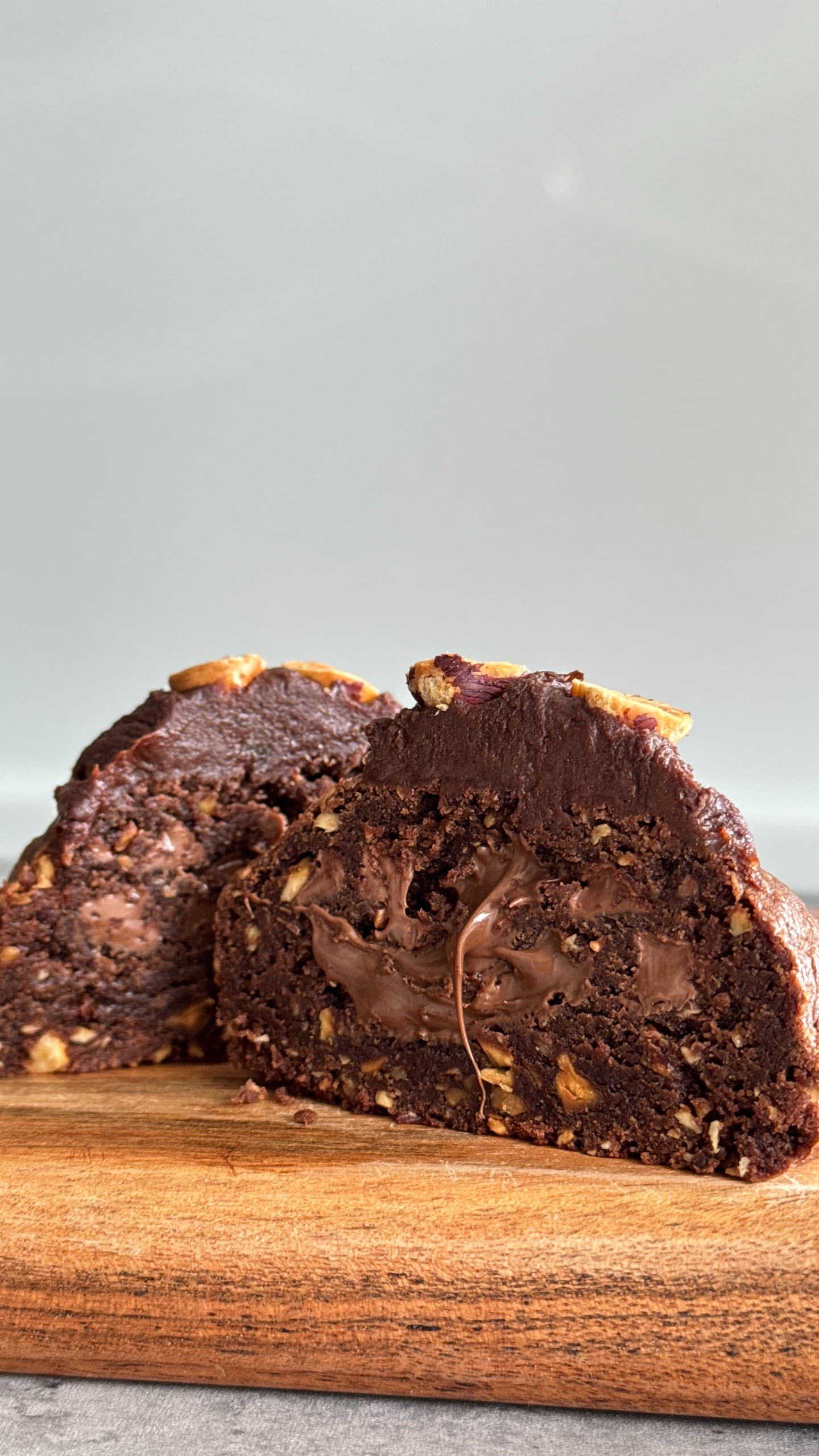 Nutella cookie topped with roasted hazelnuts on a light background.
