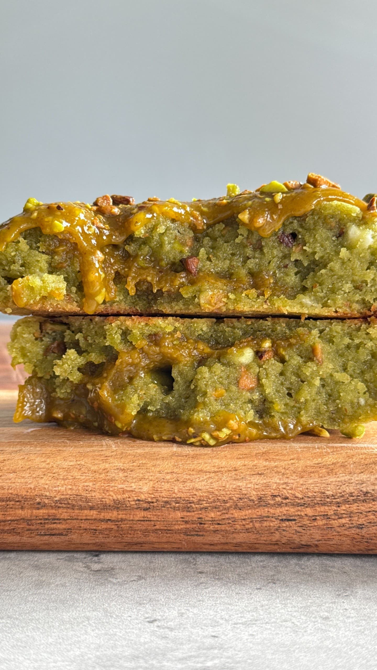 Soft pistachio cookies filled with creamy white chocolate and a smooth pistachio ganache center, showing a buttery, nutty texture with a melt-in-your-mouth appearance.