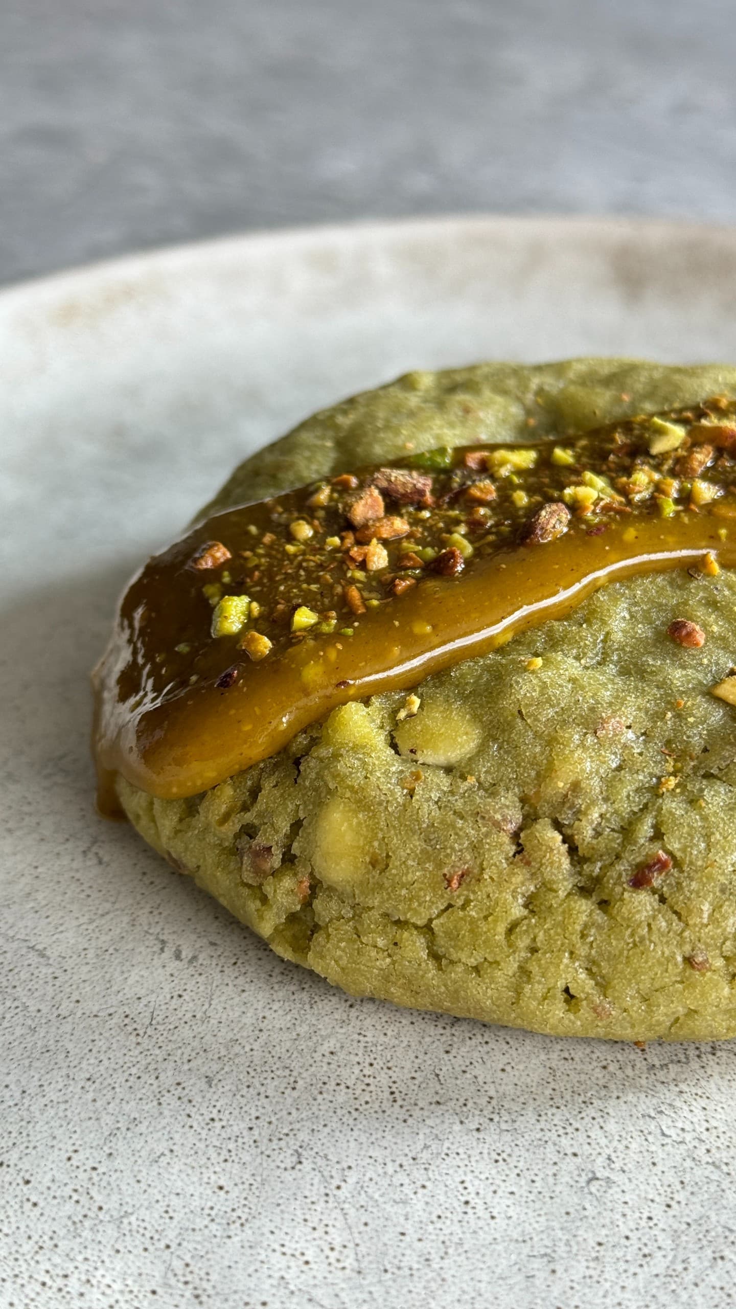 Soft pistachio cookies filled with creamy white chocolate and a smooth pistachio ganache center, showing a buttery, nutty texture with a melt-in-your-mouth appearance.